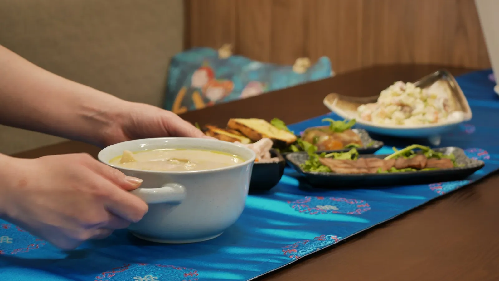 A bowl of soup being set down at a table already laid with entrées